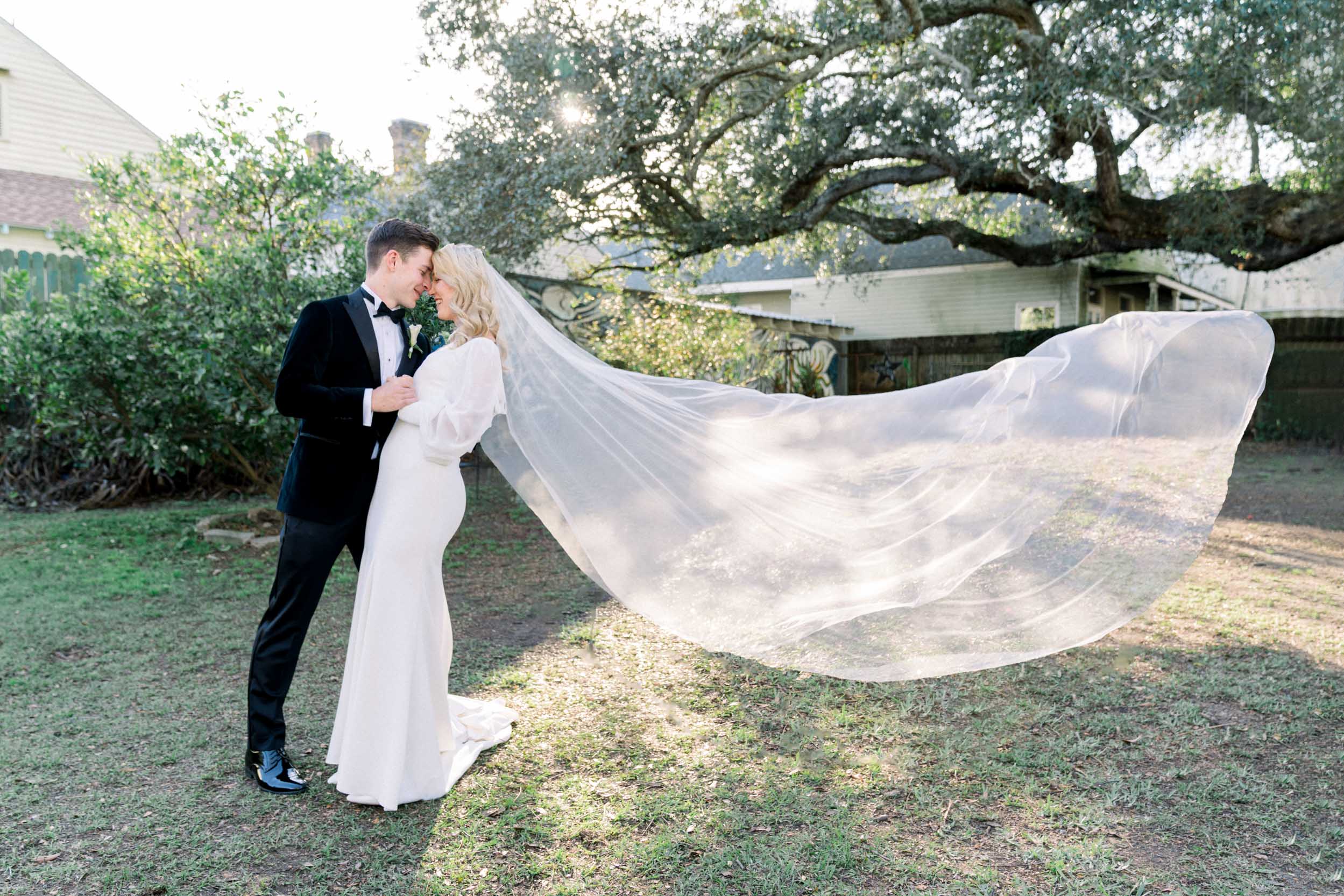 bride's veil flying in the air and kissing groom at Clouet Gardens in New Orleans