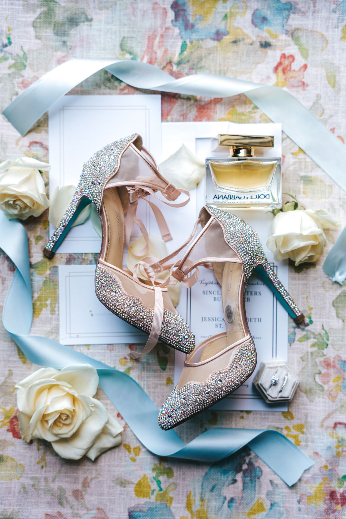 wedding flat lay with shoes, perfume,invitations, and rings