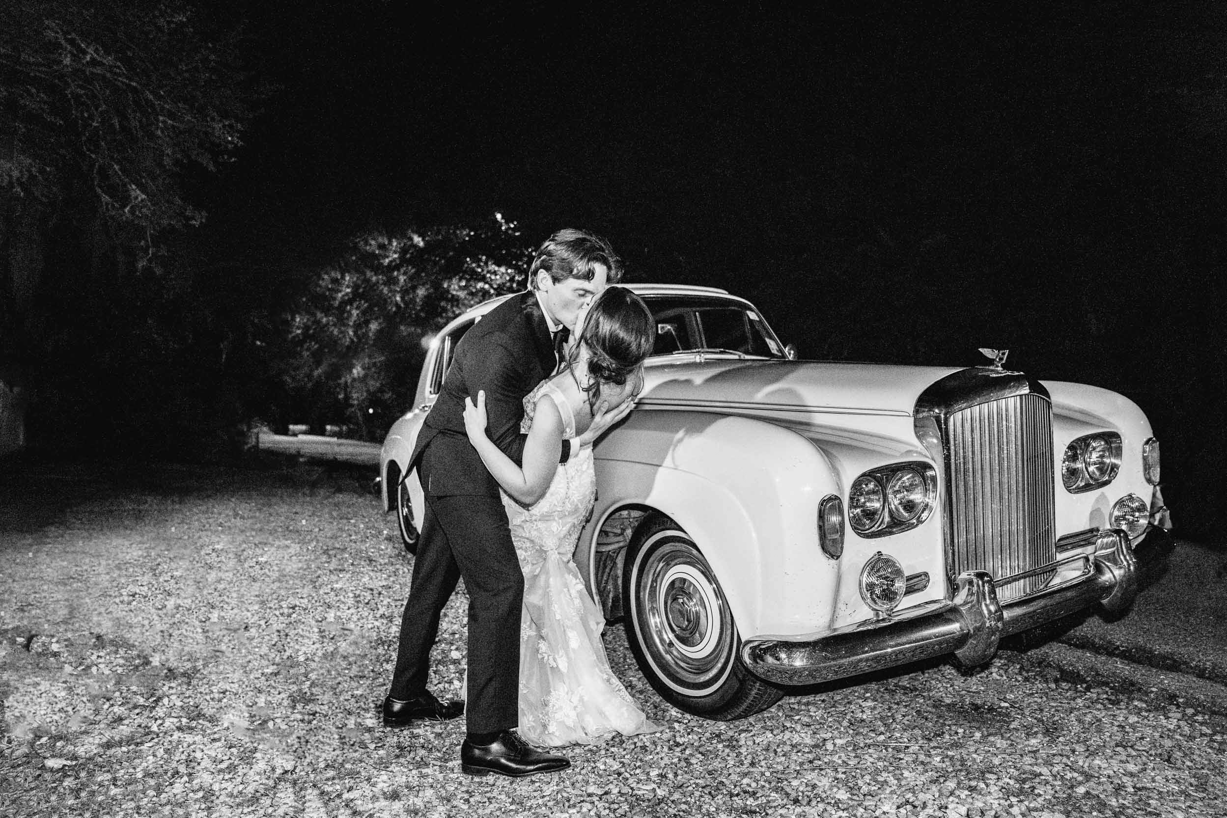 bride and groom kissing in front of old car at Maison Lafitte in Covington, Louisiana