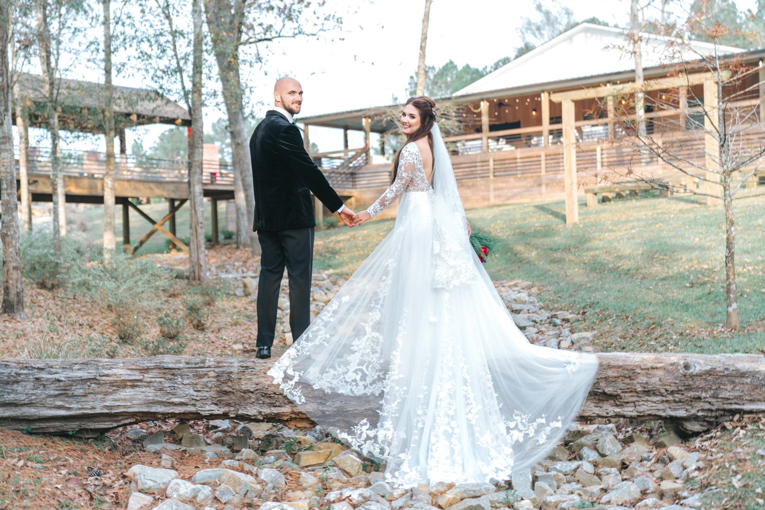 Bride and groom standing on log and creek at Creekview Barn in Mississippi