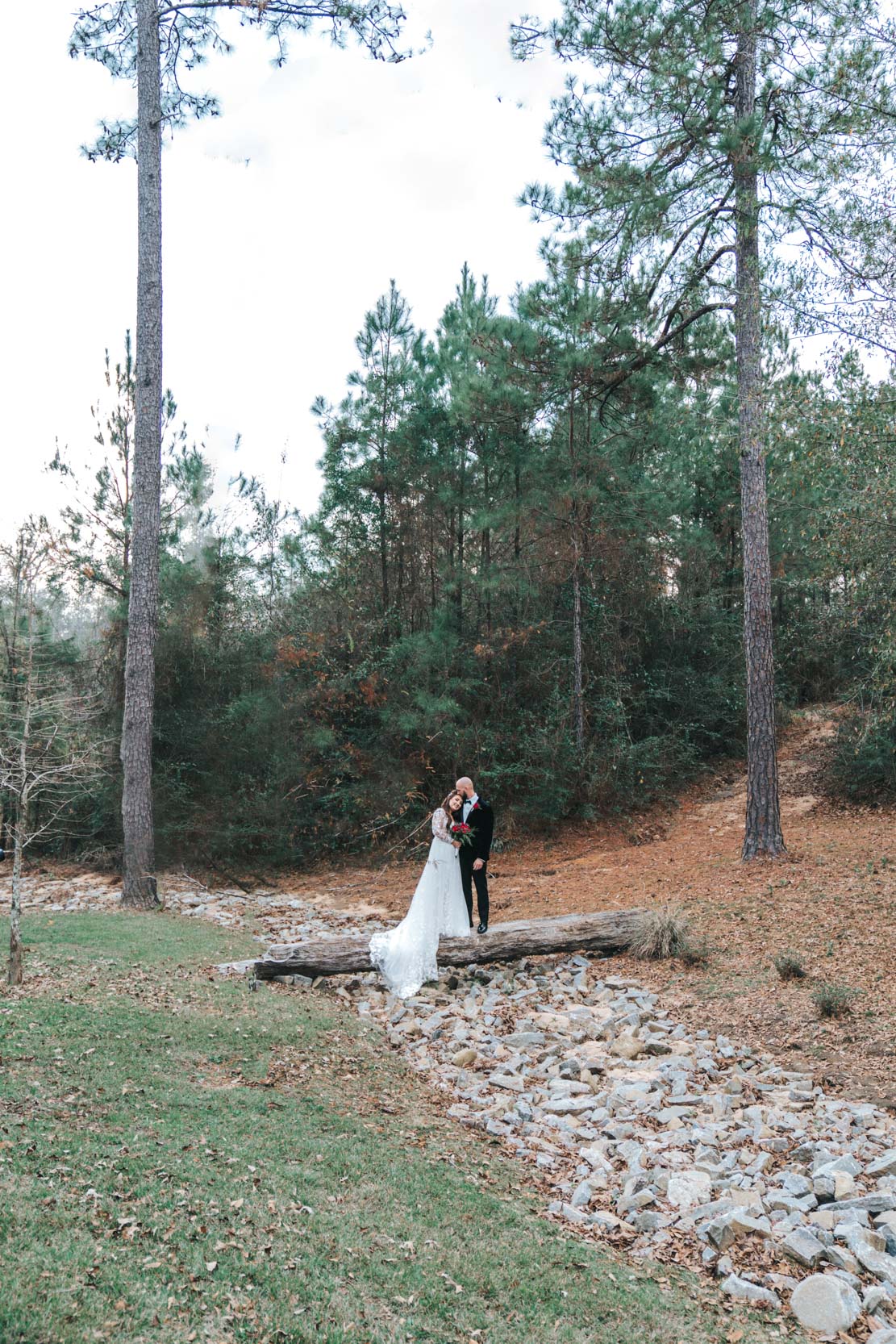 Bride and groom standing on log at Creekview Barn in Mississippi