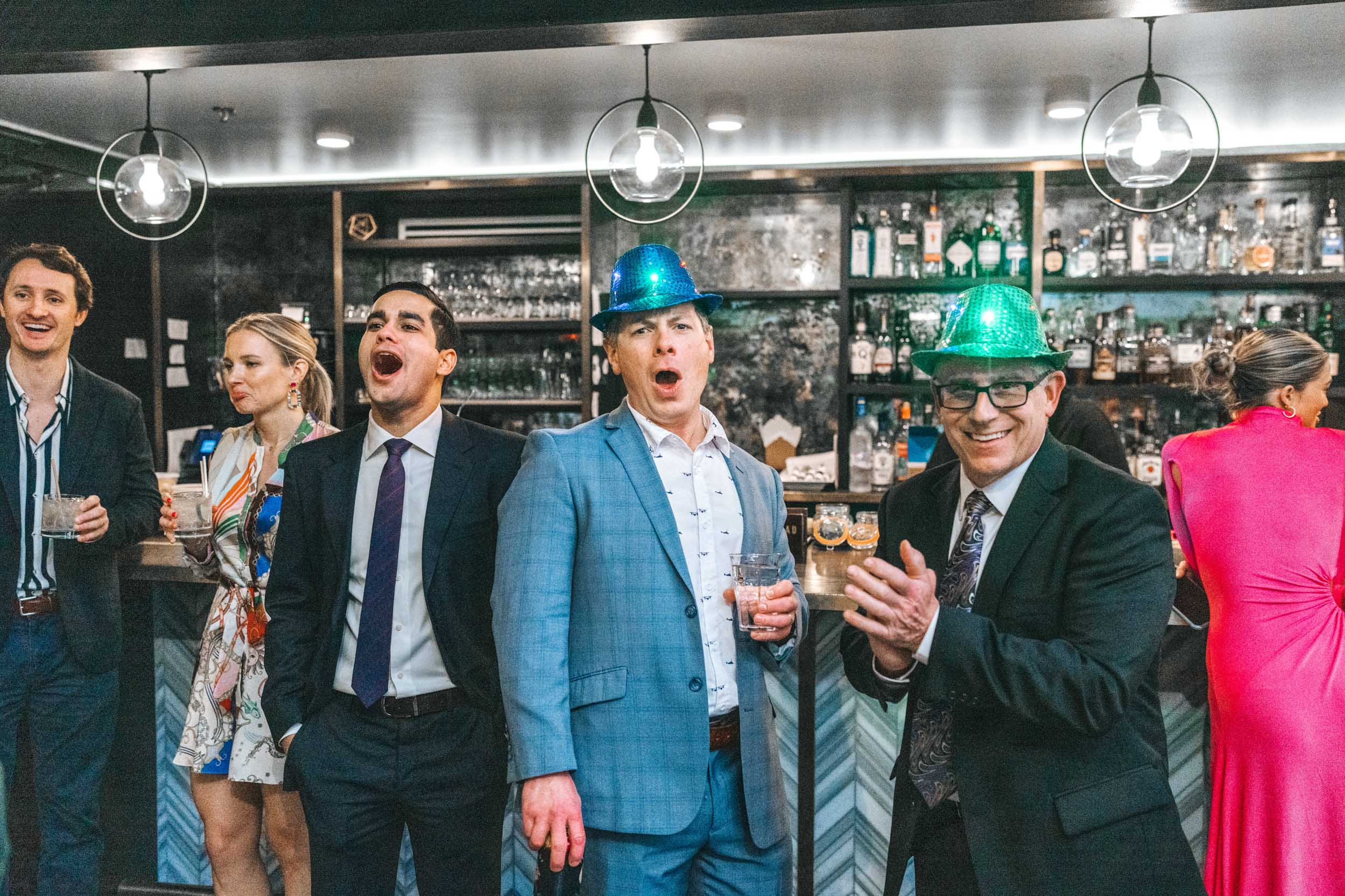 Wedding guests wearing hats and celebrating at Capulet bar in New Orleans