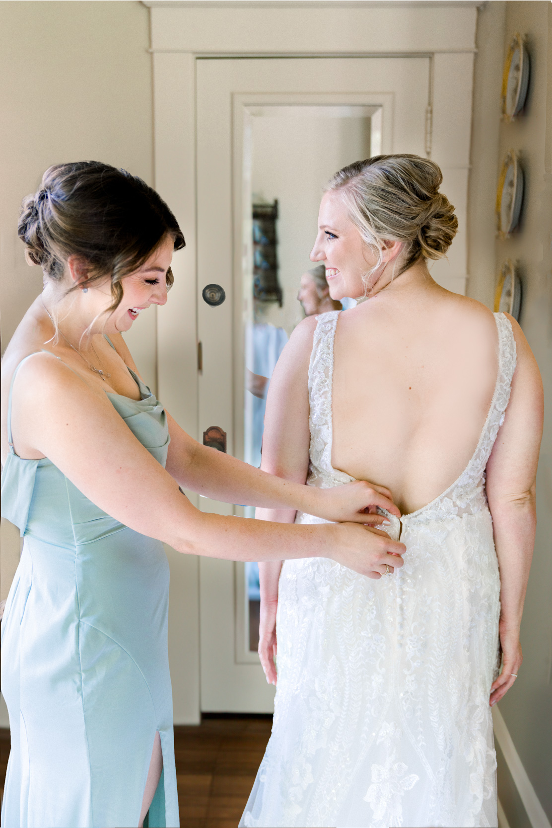 Maid of Honor buttoning bride's dress